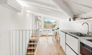 Uma cozinha moderna com fogão embutido, pia e janela com vista para uma varanda.