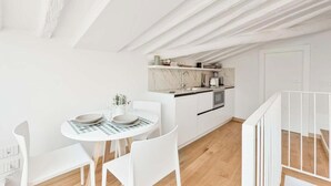 Una cocina moderna con armarios blancos, salpicadero de mármol y horno empotrado.