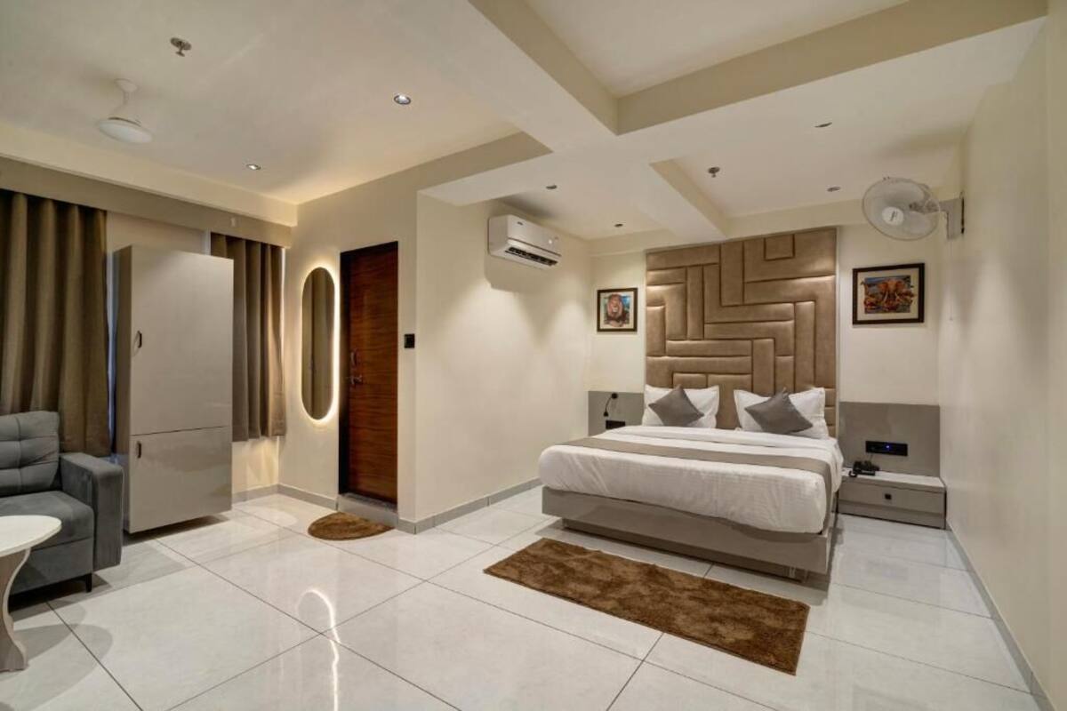 Une chambre moderne avec un grand lit, un canapé, une petite table et une armoire.