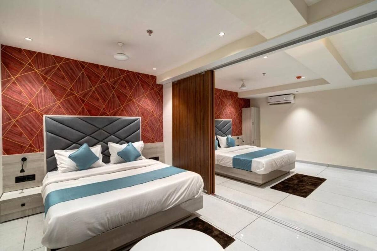 Une chambre d’hôtel moderne dotée d’un grand lit, d’un coin salon séparé et d’un mur recouvert de miroirs.