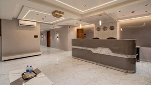 Un hall d’hôtel moderne avec un comptoir d’accueil, un grand lit et un lustre.