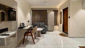Un salon moderne et bien éclairé, avec un canapé, une table basse et un téléviseur fixé au mur.