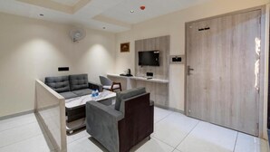 Un salon moderne avec un canapé, une petite table, un téléviseur fixé au mur et une porte en bois.