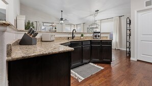 A modern kitchen with dark cabinetry, granite countertops, and a central island. - Group Getaway with Games & Hot Tub! (Loveland)