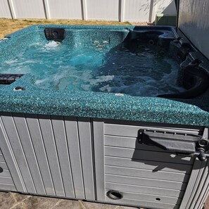 Un jacuzzi con superficie texturizada, panel de control y desagüe.