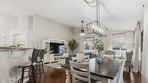 A spacious living room with a large dining table, white chairs, a TV, and a ceiling fan. - Group Getaway with Games & Hot Tub! (Loveland)