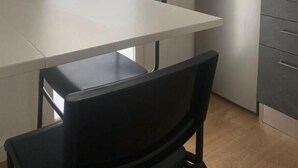 A small kitchen with a white table, black chairs, a stainless steel refrigerator, and a white door. - The Attico (Bari)