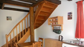 A kitchen with wooden cabinets, a sink, a stove, and a wooden staircase. - Loré Cottage Near Amboise and Chenonceaux (Montlouis-sur-Loire)