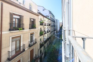 A narrow urban street with multi-story buildings, balconies, and a canal. - 2-Bedroom Apartment Steps Away from Gran Vía: Live in the Heart of Madrid (Madrid)
