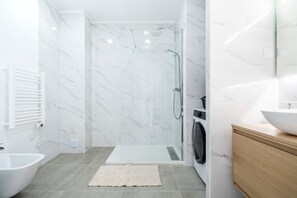 A modern bathroom with a glass-enclosed shower, a white sink, and a wooden vanity.