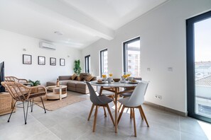 Un salon moderne comprenant une table à manger, des chaises, un canapé et un téléviseur.