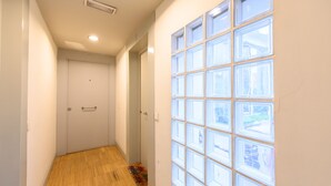Un couloir doté d’un plancher en bois, d’une porte blanche et d’un mur percé de nombreuses fenêtres.