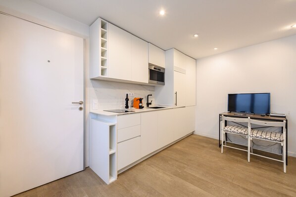A modern kitchen with white cabinetry, a built-in oven, and a small dining area with a table and chairs. - (TES314E) Cozy Studio in the Center of Madrid (Madrid)