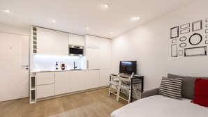 Un espace de vie compact comprenant un coin cuisine, un espace repas et un lit.