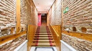 Un escalier avec des rampes en bois et une moquette rouge menant à une porte située en haut.