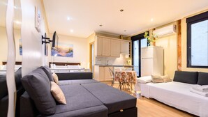 Un salon moderne avec un canapé gris, un canapé blanc et un coin repas comprenant une table et des chaises.