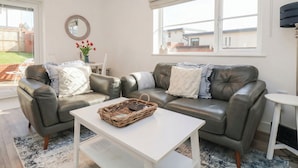 Een moderne woonkamer met een leren bank, een witte salontafel en een rieten mand.