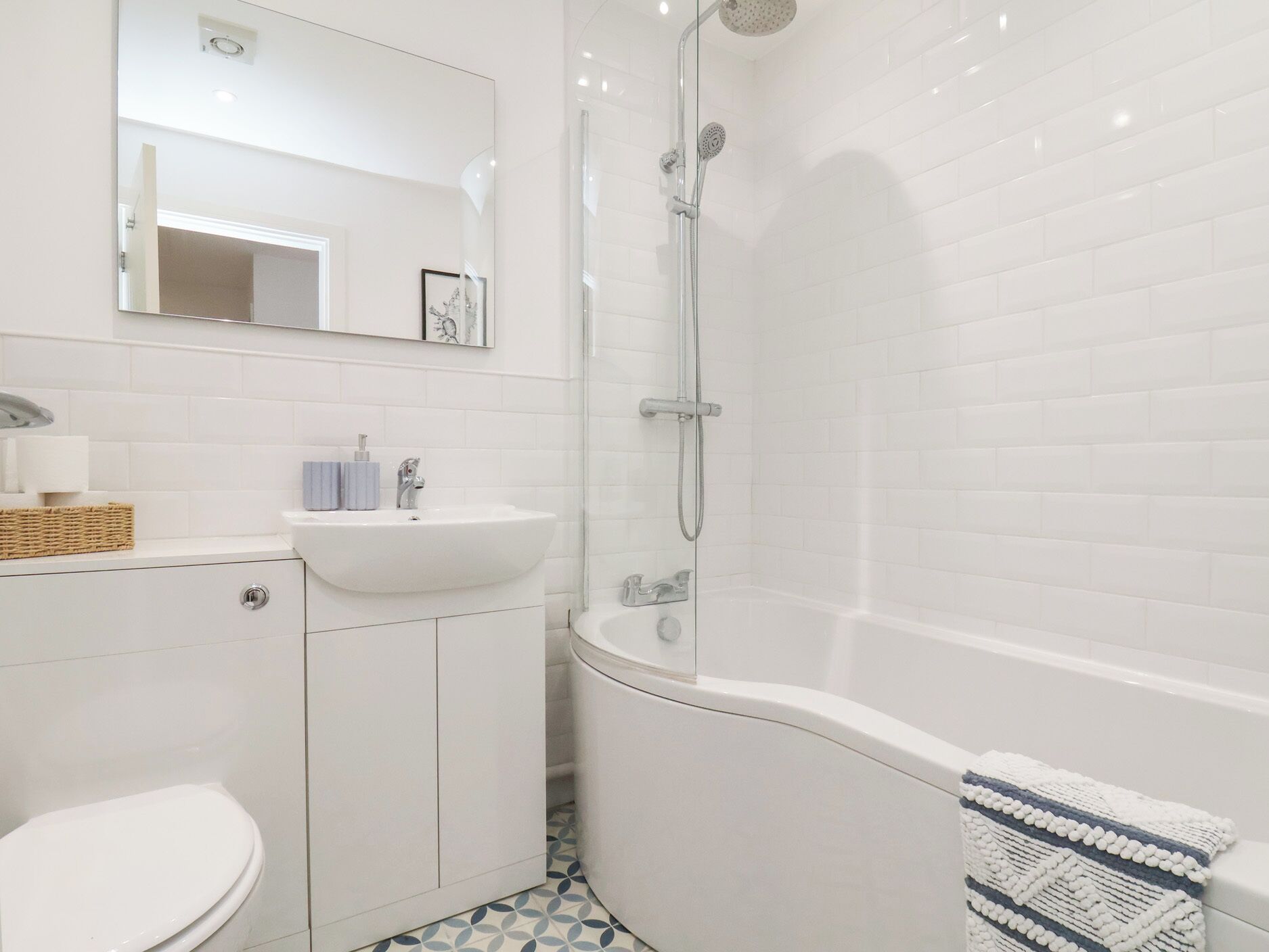 A modern bathroom with a white sink, toilet, and shower area.