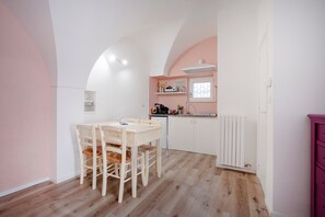 A kitchen with a dining table and chairs, a built-in oven, and a window. - Apartment 'La Casetta Rosa' (Martina Franca)