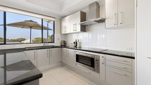 Una cocina moderna con armarios blancos, electrodomésticos de acero inoxidable y un amplio ventanal con paraguas.