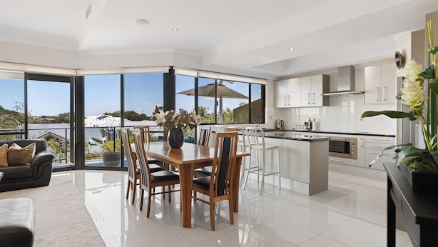 Una cocina moderna con armarios blancos, una isla central y un ventanal con vistas panorámicas.