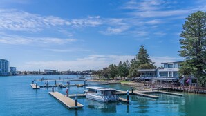 Un puerto deportivo con barcos amarrados, un restaurante frente al agua y un edificio moderno con fachada de vidrio.