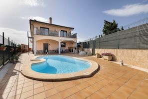 Ein zweistöckiges Haus mit Swimmingpool, Balkon und umzäunter Terrasse.