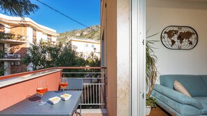 A balcony with a table and two glasses of wine, a blue sofa, and a world map clock on the wall. - YourHome - Lady Lucy Holiday Home (Meta)