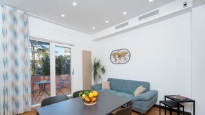 A modern living room with a dining table, a sofa, and a small side table. - YourHome - Lady Lucy Holiday Home (Meta)