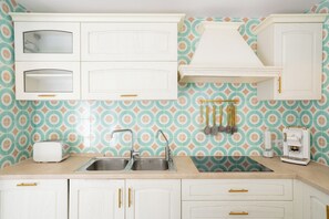 A kitchen with white cabinets, a double sink, a toaster, and a coffee maker. - Casa Monti Positano (Montepertuso)