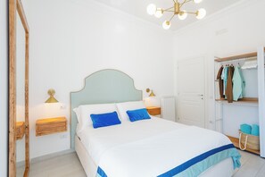A bedroom with a bed, bedside tables, a mirror, a wardrobe, and a hanging light fixture. - Casa Monti Positano (Montepertuso)