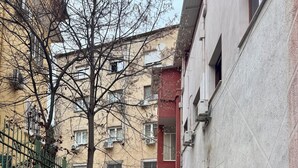 A narrow pathway flanked by buildings with a mural, a green fence, and red chairs. - Tirana Central Apartment - Free Parking - Fit Five (Tiranë)