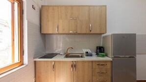 A compact kitchen with wooden cabinets, a stainless steel sink, and a built-in refrigerator. - Tirana Central Apartment - Free Parking - Fit Five (Tiranë)