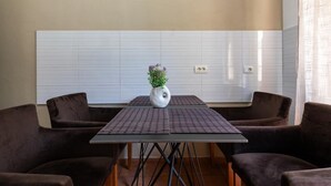 A modern kitchen with a white tiled backsplash, a central island with a vase of flowers, and two brown upholstered chairs. - Tirana Central Apartment - Free Parking - Fit Five (Tiranë)
