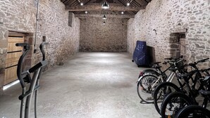 Um quarto com paredes de pedra, teto alto, equipamentos de ginástica e bicicletas.