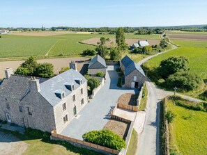A large stone building with multiple rooms and a courtyard, surrounded by fields and a rural landscape. - Large family home, completely renovated, between sea and countryside. (Réville)