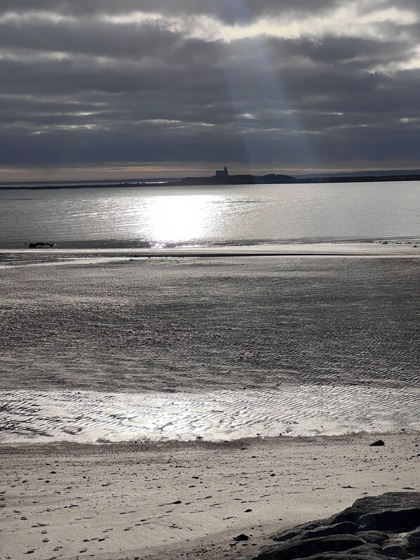 A beach with a calm sea, a distant structure, and a cloudy sky. - Large family home, completely renovated, between sea and countryside. (Réville)