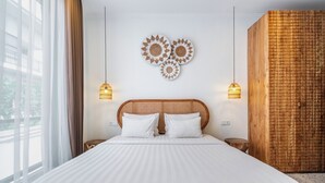 A hotel room with a large bed, two bedside tables, a headboard, and a wall-mounted decorative piece. - Ocean Breeze Berawa Villa (Canggu)