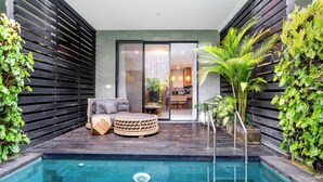 A modern outdoor pool area with a seating area, a staircase, and lush greenery. - Ocean Breeze Berawa Villa (Canggu)