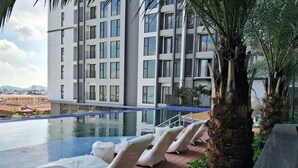 Un hotel moderno con piscina, sillones de descanso y vistas a la ciudad.