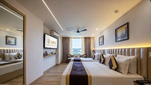 Habitación de hotel con una cama grande, televisión, ventilador de techo y vistas a la ciudad.
