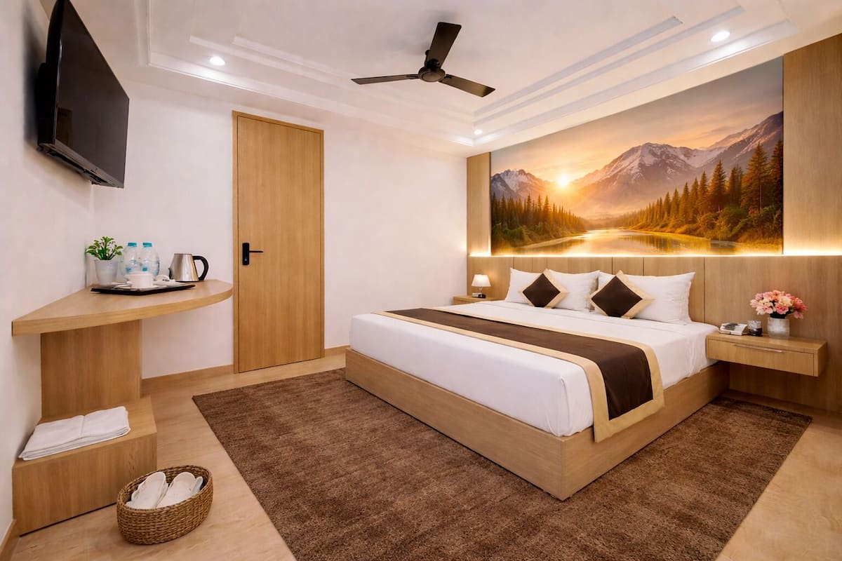 Habitación de hotel con cama, televisor de pantalla plana, escritorio de madera, cuadro colgado en la pared y ventilador de techo.