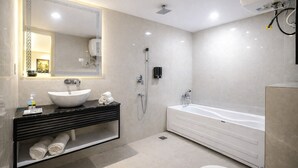 Un baño moderno con una bañera blanca grande, un lavamanos sobre encimera, un cabezal de ducha de mano y un inodoro.