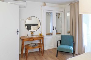 Een kamer met een houten bureau, een stoel, een spiegel, een kledingkast en een bed.