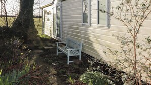 A mobile home with a bench outside, surrounded by vegetation. - Rhosgranog Caravan (Haverfordwest)