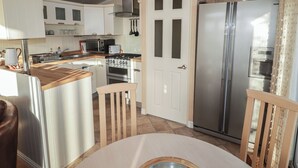 A compact kitchen with a central island, a refrigerator, a microwave, and a stove. - Rhosgranog Caravan (Haverfordwest)