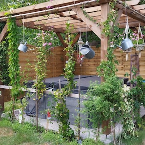 A wooden pergola with hanging pots and climbing plants.