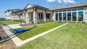 Une maison à deux étages dotée d’une grande véranda à l’avant, d’un patio couvert et d’une pelouse bien entretenue.