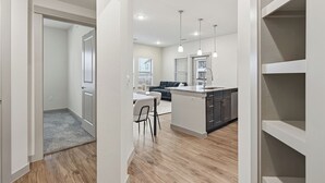 Une cuisine moderne dotée d’un îlot central, un coin repas avec une table et des chaises, et un espace de vie avec un canapé et une table basse.