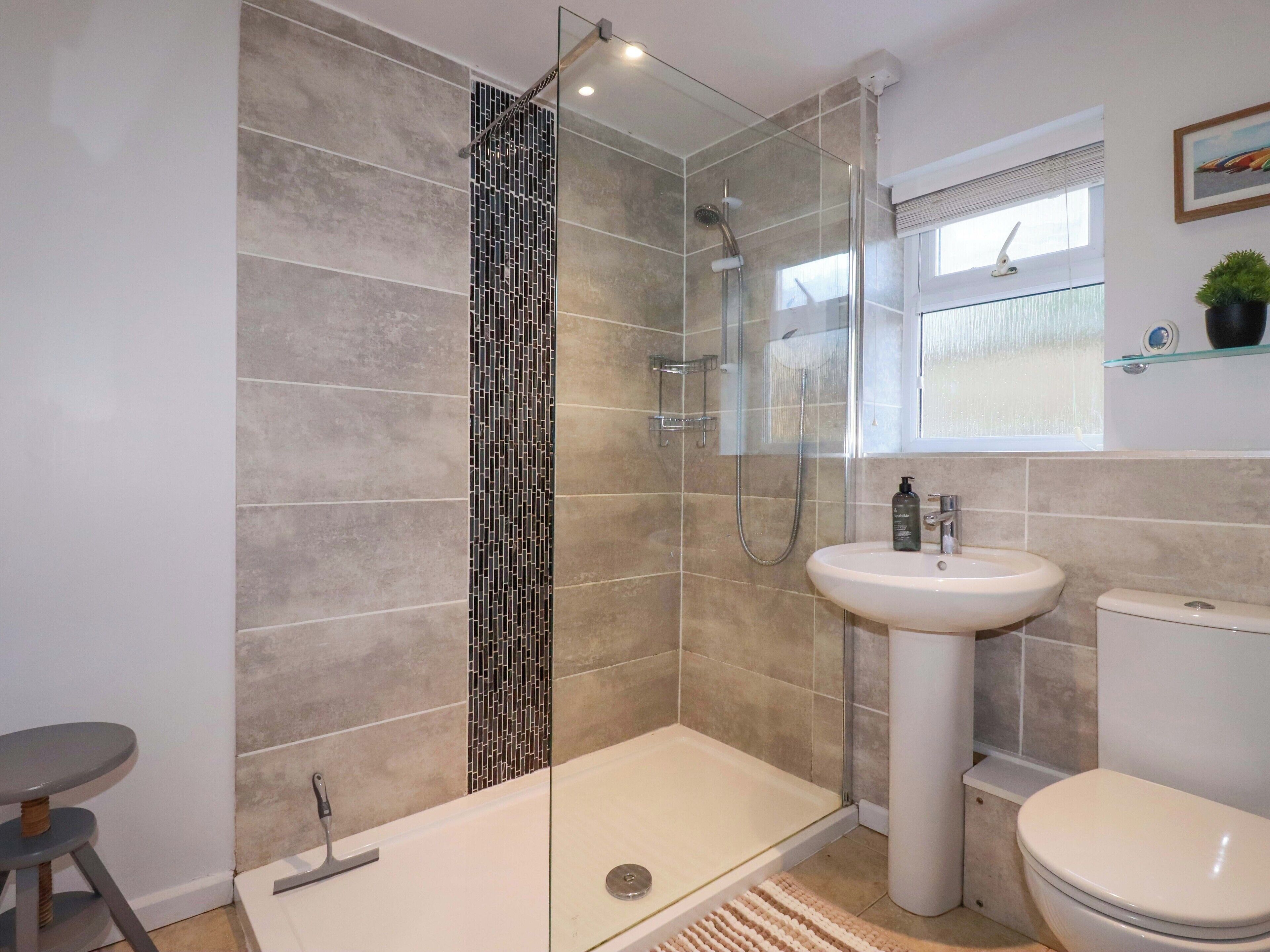 A modern bathroom with a glass-enclosed shower, a white sink, and a toilet.